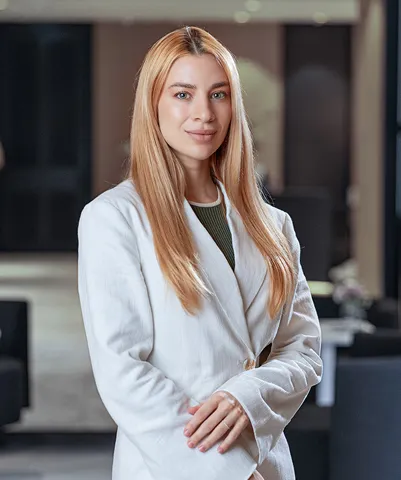 Confident blonde clinician in a white coat standing in a modern clinic